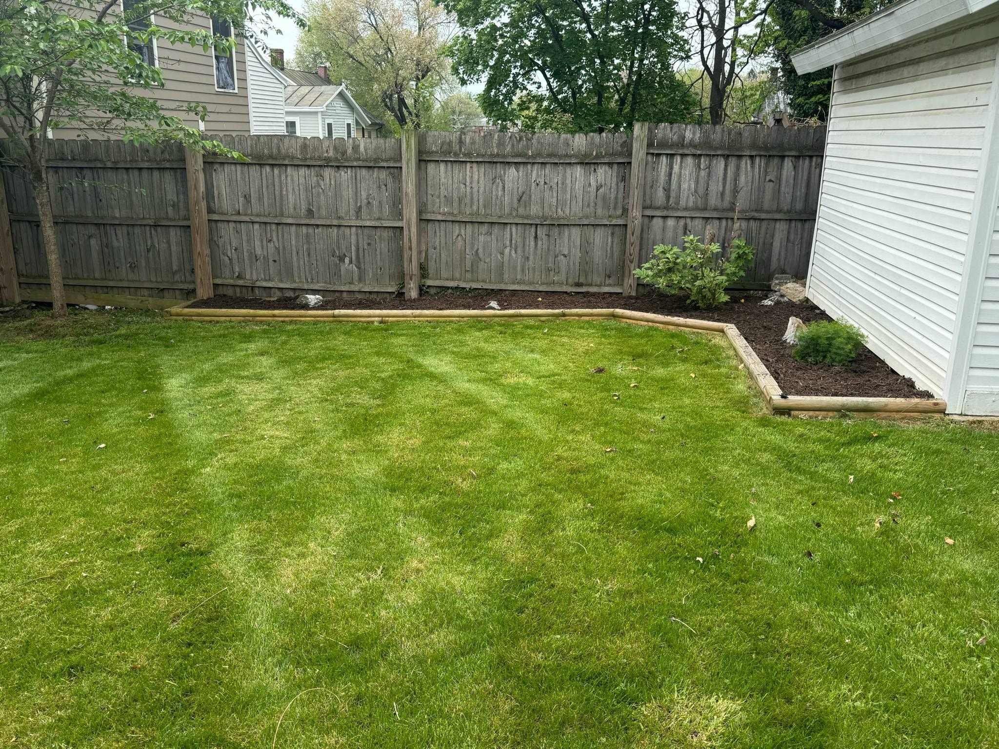 Backyard lawn care with timber edging and mulch beds in Winchester VA